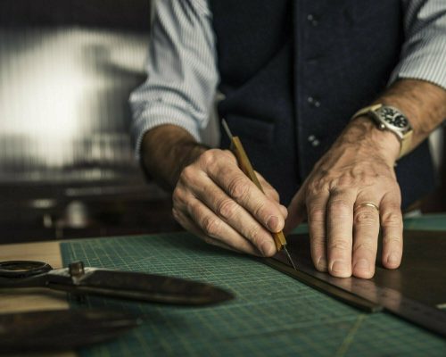 Close up shoot of an artisan working with leather in his laboratory.